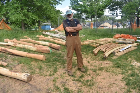 Cambridge artist Mitch Ryerson with the lumber he's turning into a Sensory Hilltop for the Universal Design Playground at Cambridge's Danehy Park, May 27, 2021. (Cambridge Arts / Greg Cook)
