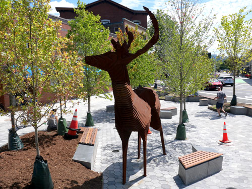 Mark Reigelman's “Edge of the Forest,” a 12-foot-tall steel sculpture of a deer, in Cambridge’s Inman Square, 2023.
