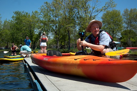 Richard Hackel sets up his camera on the kayak at the Charles River dock.