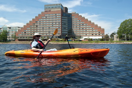 Photographer Richard Hackel kayaks past the Hyatt Regency hotel in Cambridge, along the Charles River.