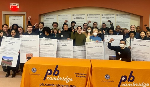 Image of people holding signs of winning projects from the Participatory 9 Budgeting Process