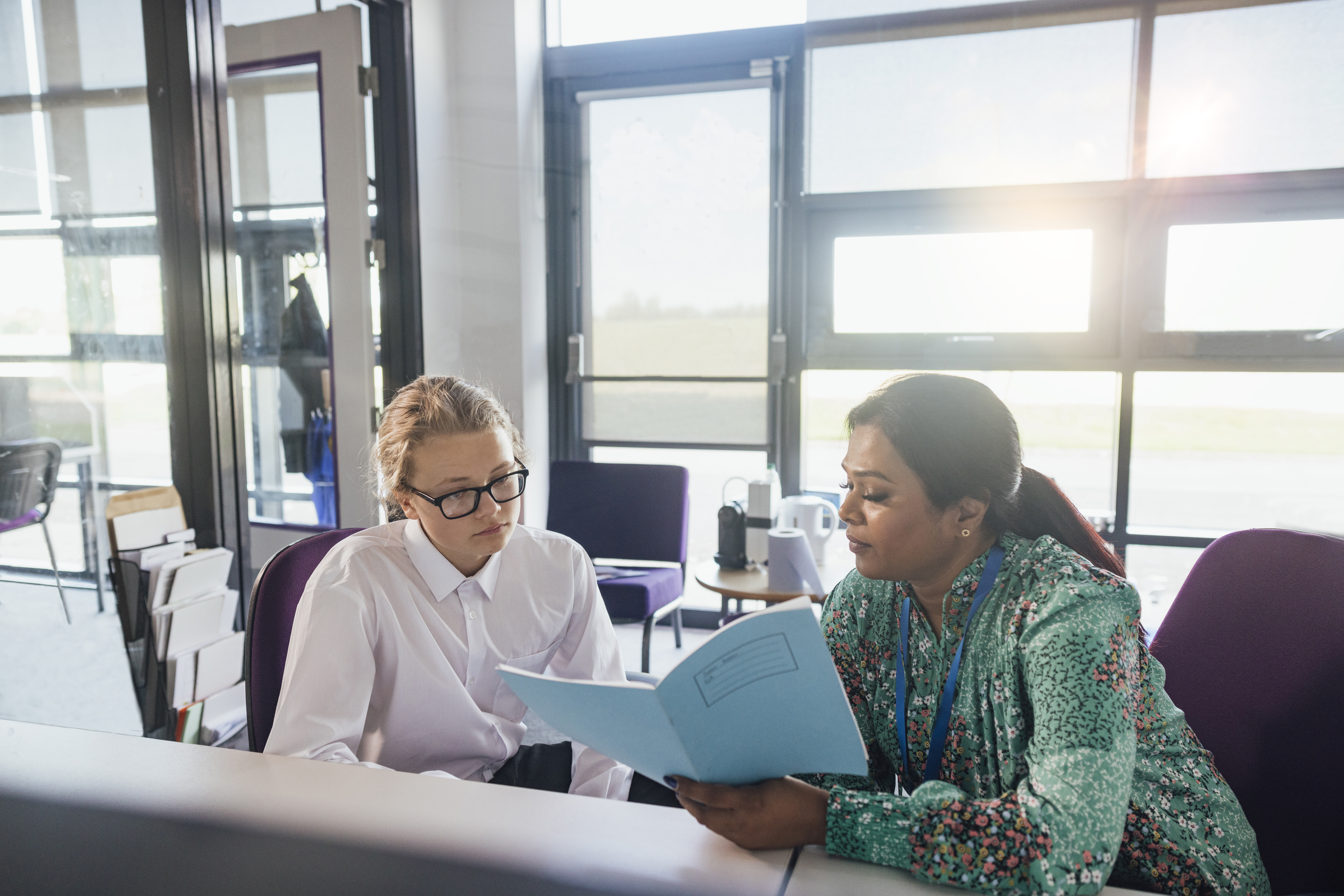 Two people sit in an office reviewing a document
