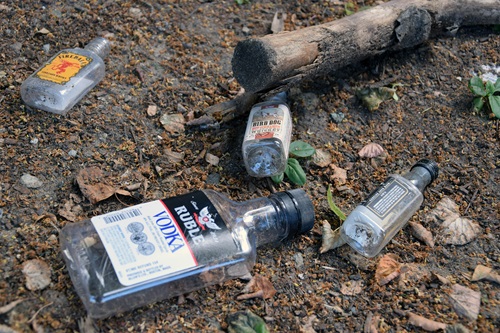 Several discarded small bottles of alcohol lying on the ground