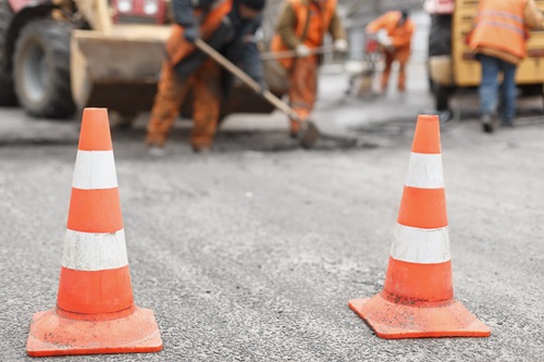 Photo of two construction cones with construction workers in the background