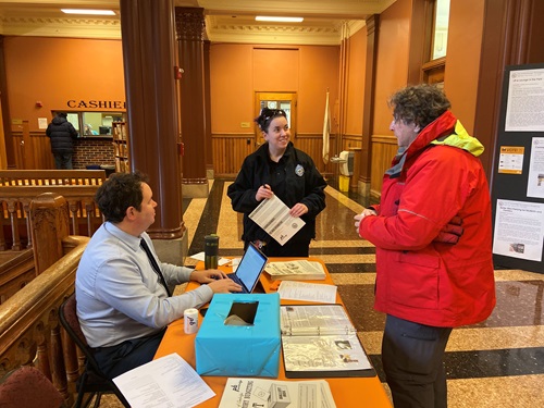 Photo of two residents and a city representative speaking about Participatory Budgeting at a Participatory Budgeting table.