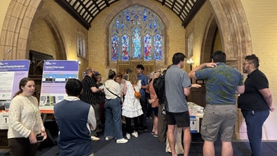 room full of people standing talking looking at large boards set on aisles