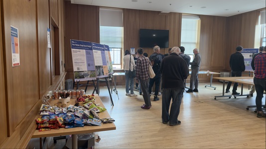 table with snack on the left side forground and people standing in the background indoors