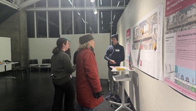 group of people standing in front of a gallery wall that has a map and boards hung up