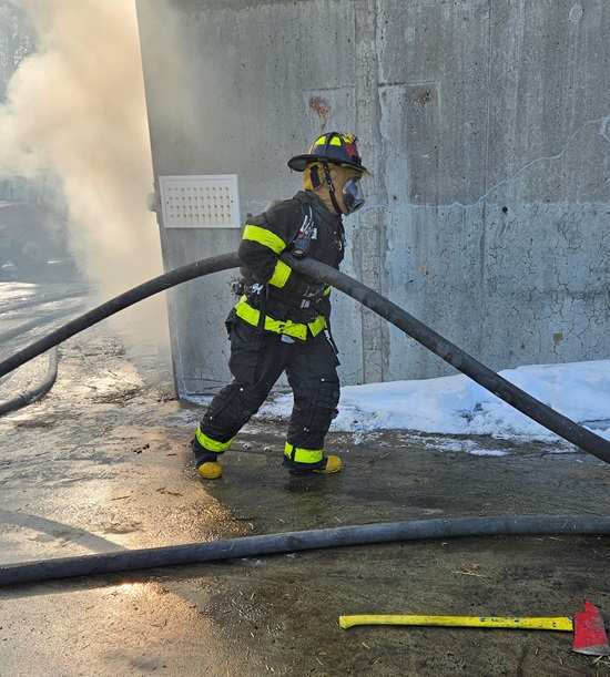 A Cambridge recruit firefighter advancing a hose line to the burn training building - MA Fire Academy - Stow, MA