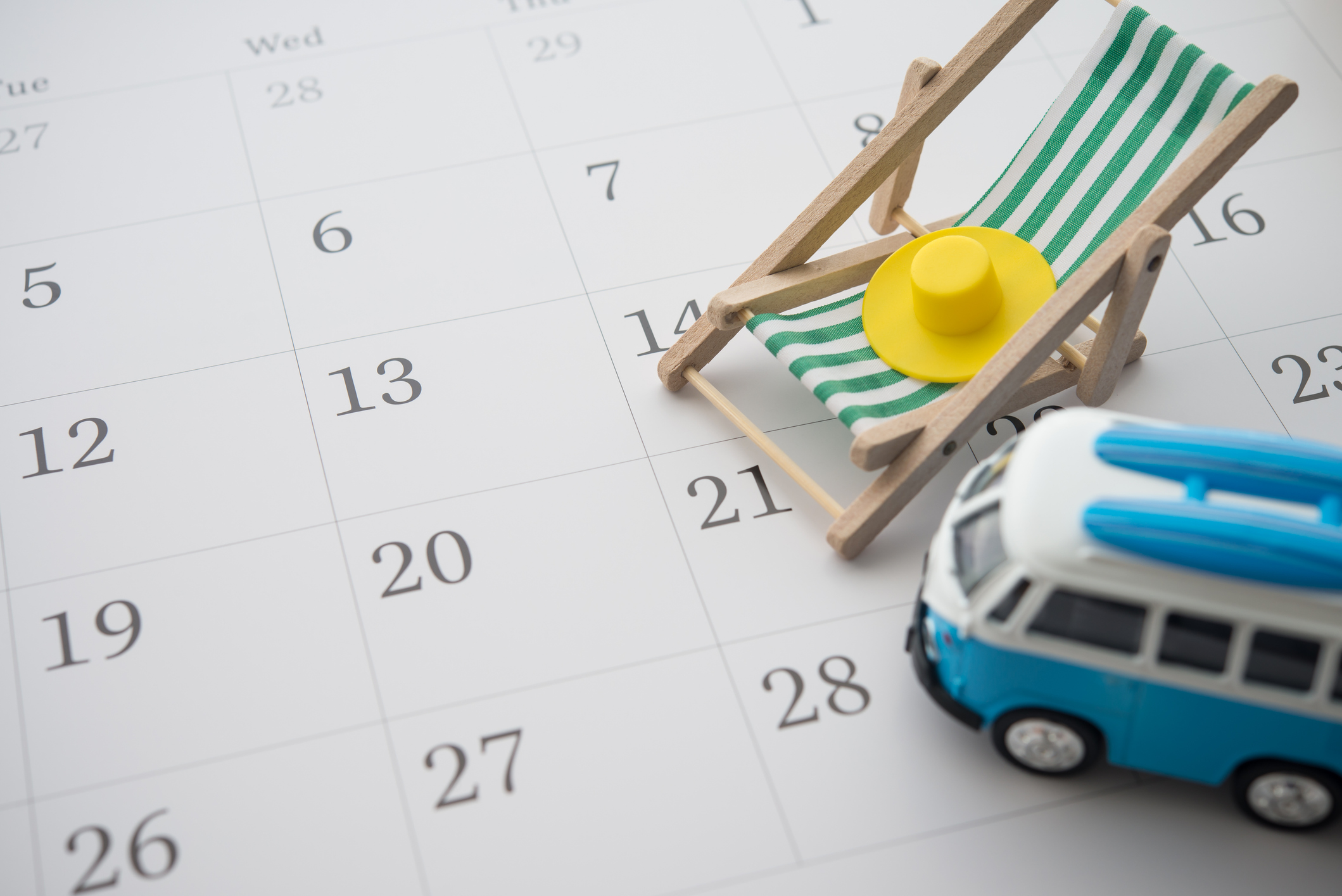 A model beach chair and micro bus sit on top of a calendar