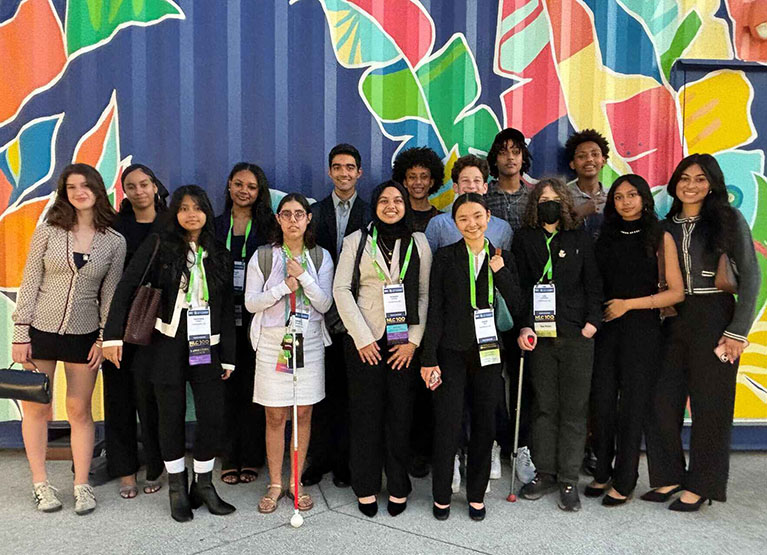A group of youth from the Cambridge Youth Council wearing formal clothes are standing, posing for a photo
