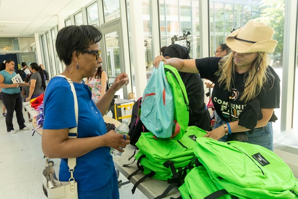 Woman receiving a backpack from a volunteer at a Cambridge Public School back to school event