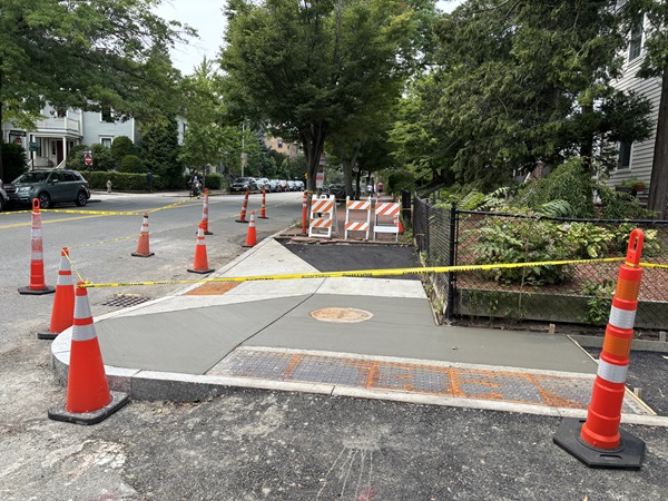 A cross walk that has recently had its concrete poured and is still roped off for drying.