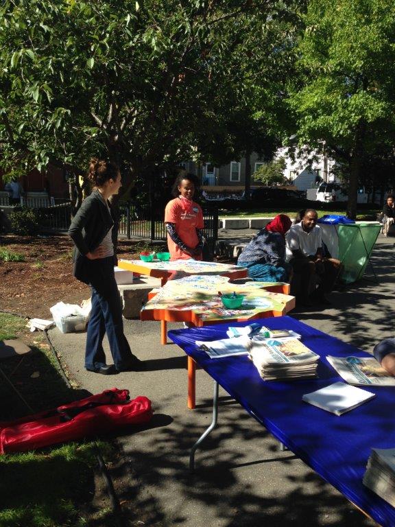 People standing at tables set up in a park