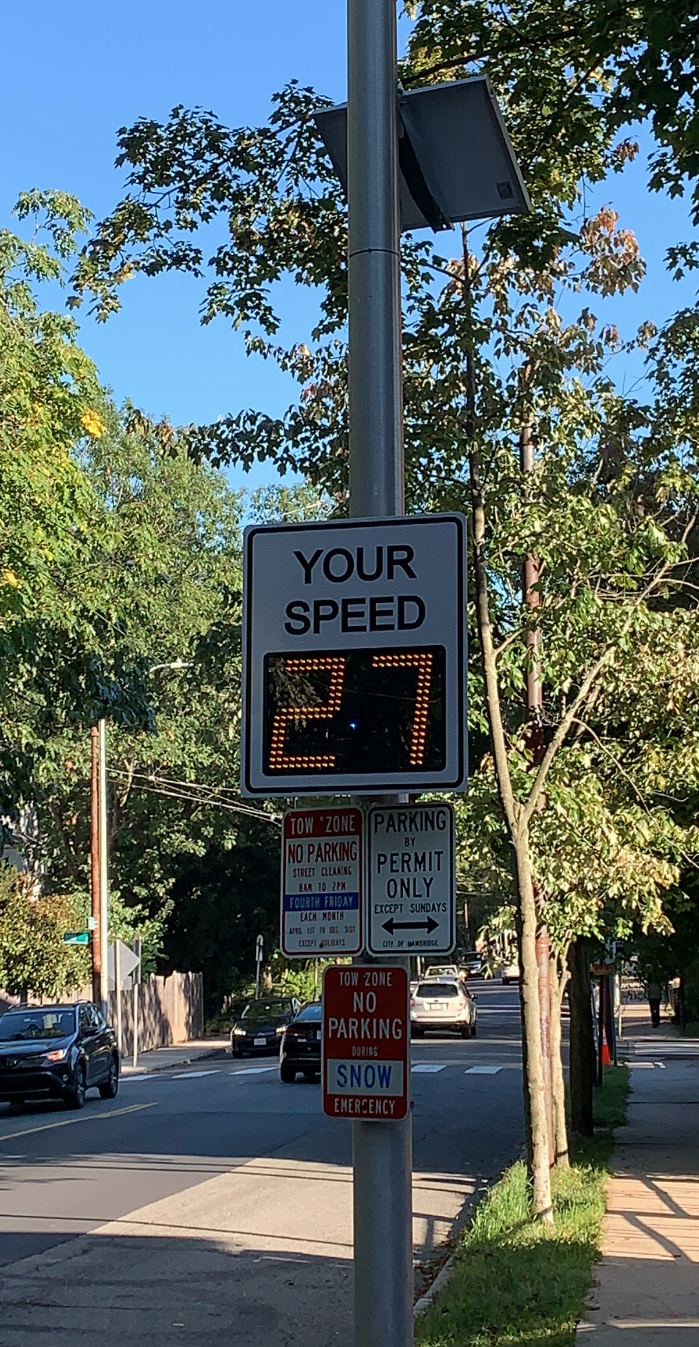 A sign with a digital display indicating a car traveling at 27 MPH