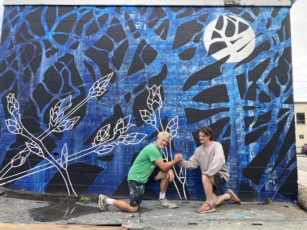 Peter Gibson and Donny Morin kneel in front of completed 333 webster mural