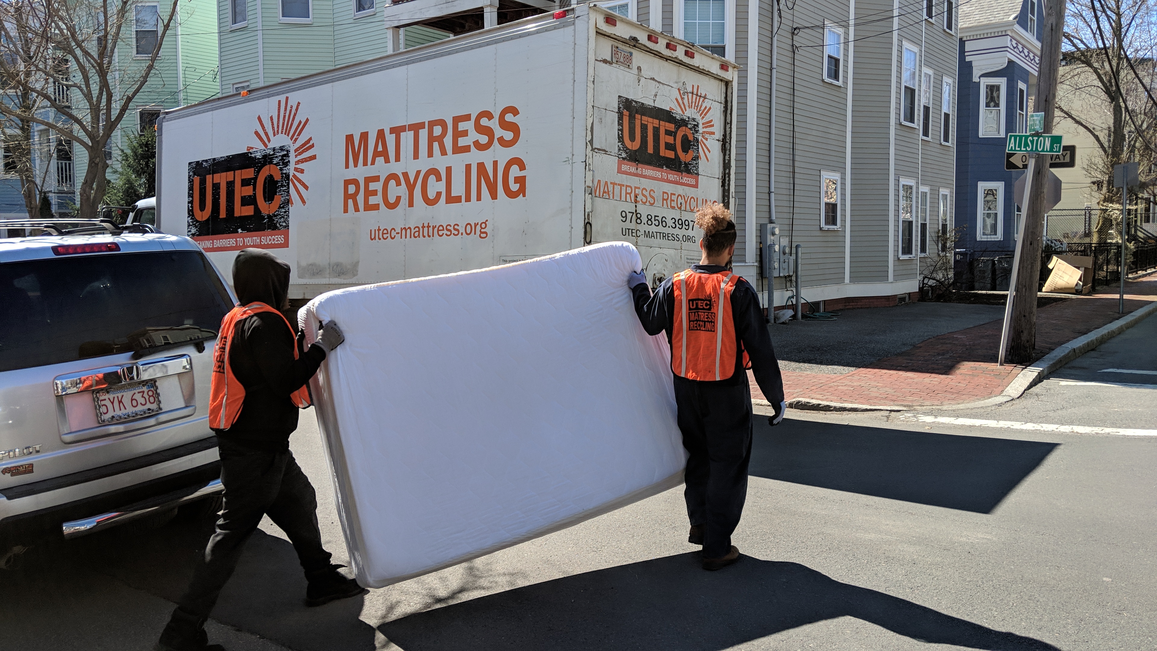 Two people carrying a mattress to a truck