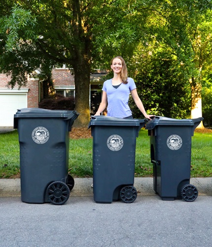 Woman standing with different sizes of trash carts