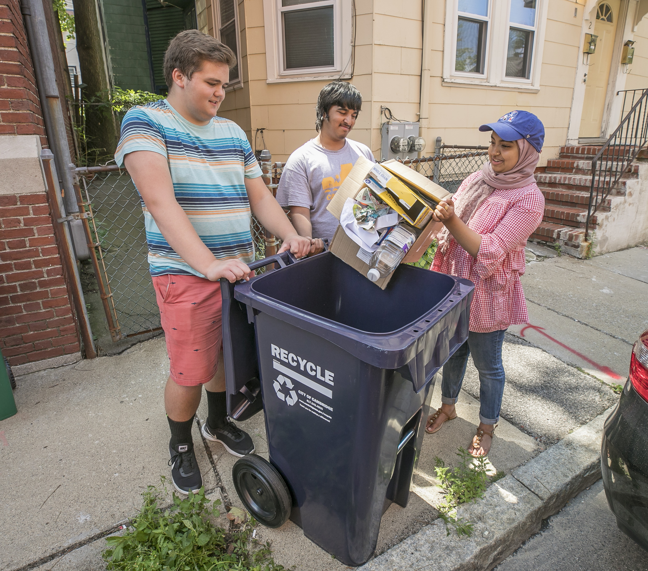 A group of people placing recyclables in a recycling bin
