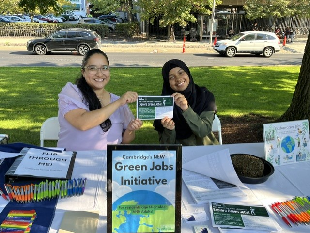 Rebecca Arellano, Cambridge Green Jobs Specialist, and her intern display a postcard about green jobs.