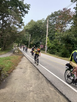 People biking up a hill and waving