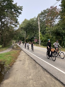 People biking up a hill and waving