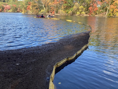 Waltham Fire Department practice deploying a boom across Hobbs Brook Reservoir to contain peat moss (simulated spill material)