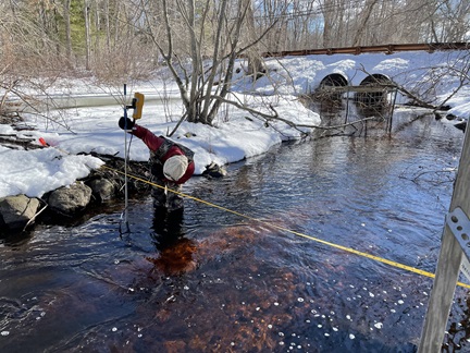 A person measures streamflow during winter at the Hobbs Brook at Mill St tributary monitoring station.