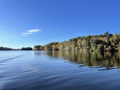 An image of serene water on Hobbs Brook Reservoir and trees on the shoreline