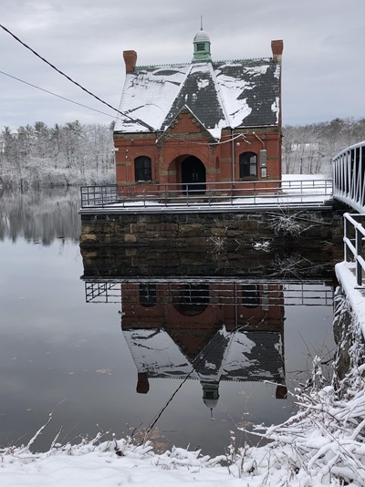 A red brick gatehouse building covered in snow on the Stony Brook Reservoir dam