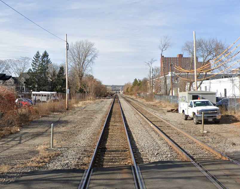 Photo taken from Sherman Street looking west at the MBTA Fitchburg Commuter Rail train tracks in North Cambridge