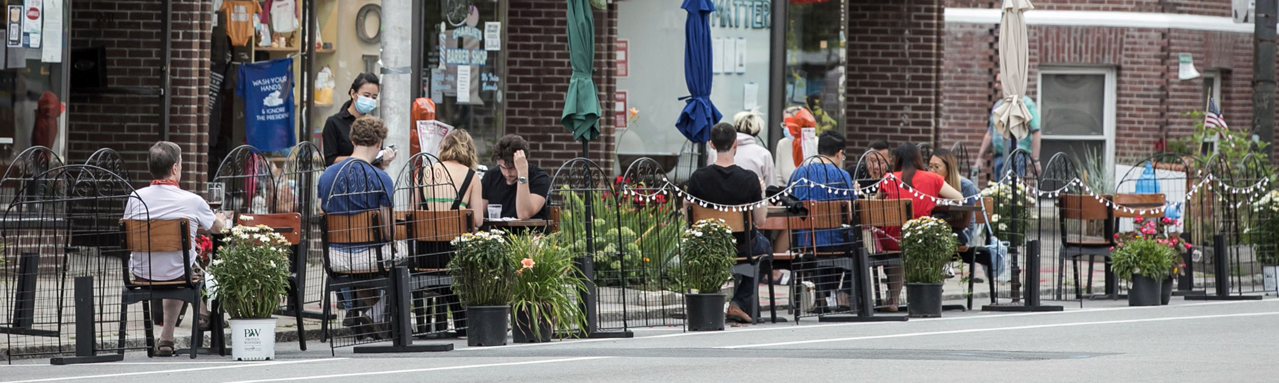 people sitting outside at tables on the street