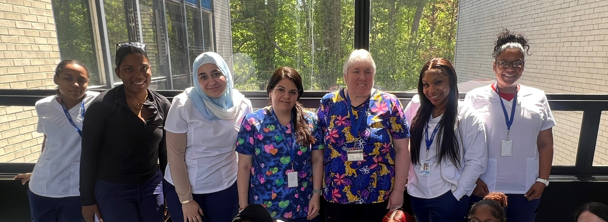 CNA participants smile in their scrubs at a hospital.