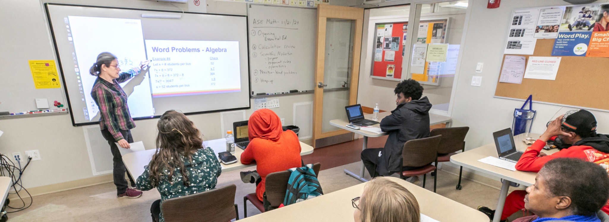 a classroom of students looks at a projector screen