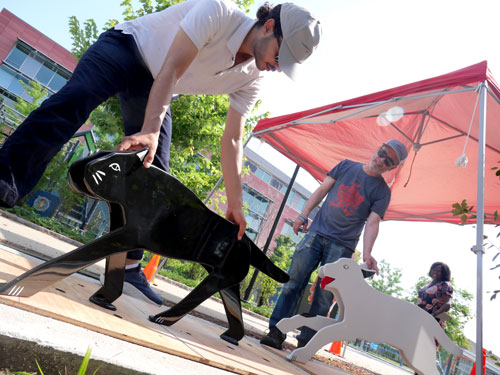 Oussama Ouadani (left) and Craig Uram of Cambridge Arts reinstall Jay Coogan's sculptures of cats and dogs at Cambridge’s King Open / Cambridge Street Upper School, Valente Branch Library, and Community Complex.