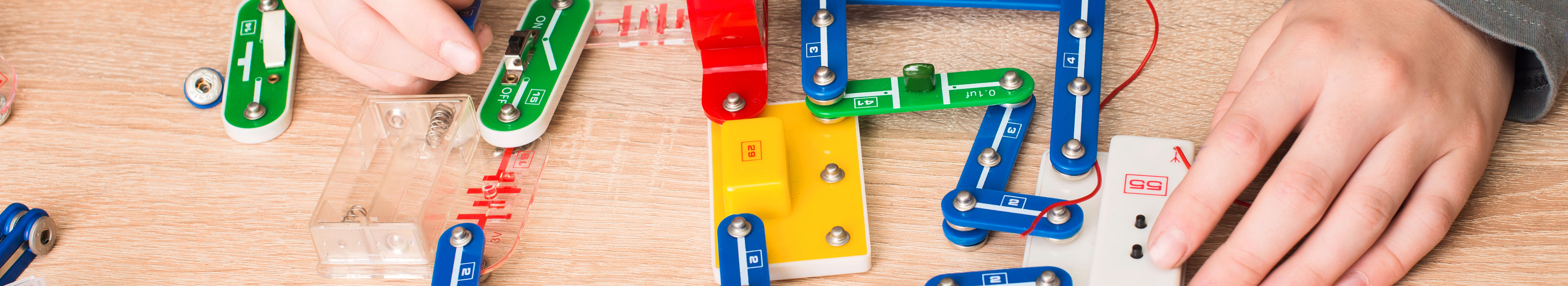 Closeup of student hands with parts of electronic constructor