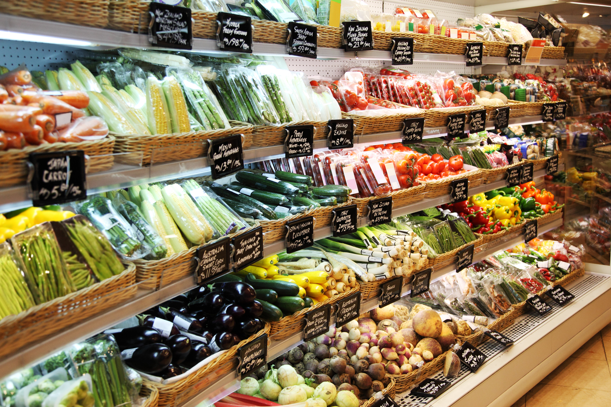 Produce in a market displayed on shelves with price tags