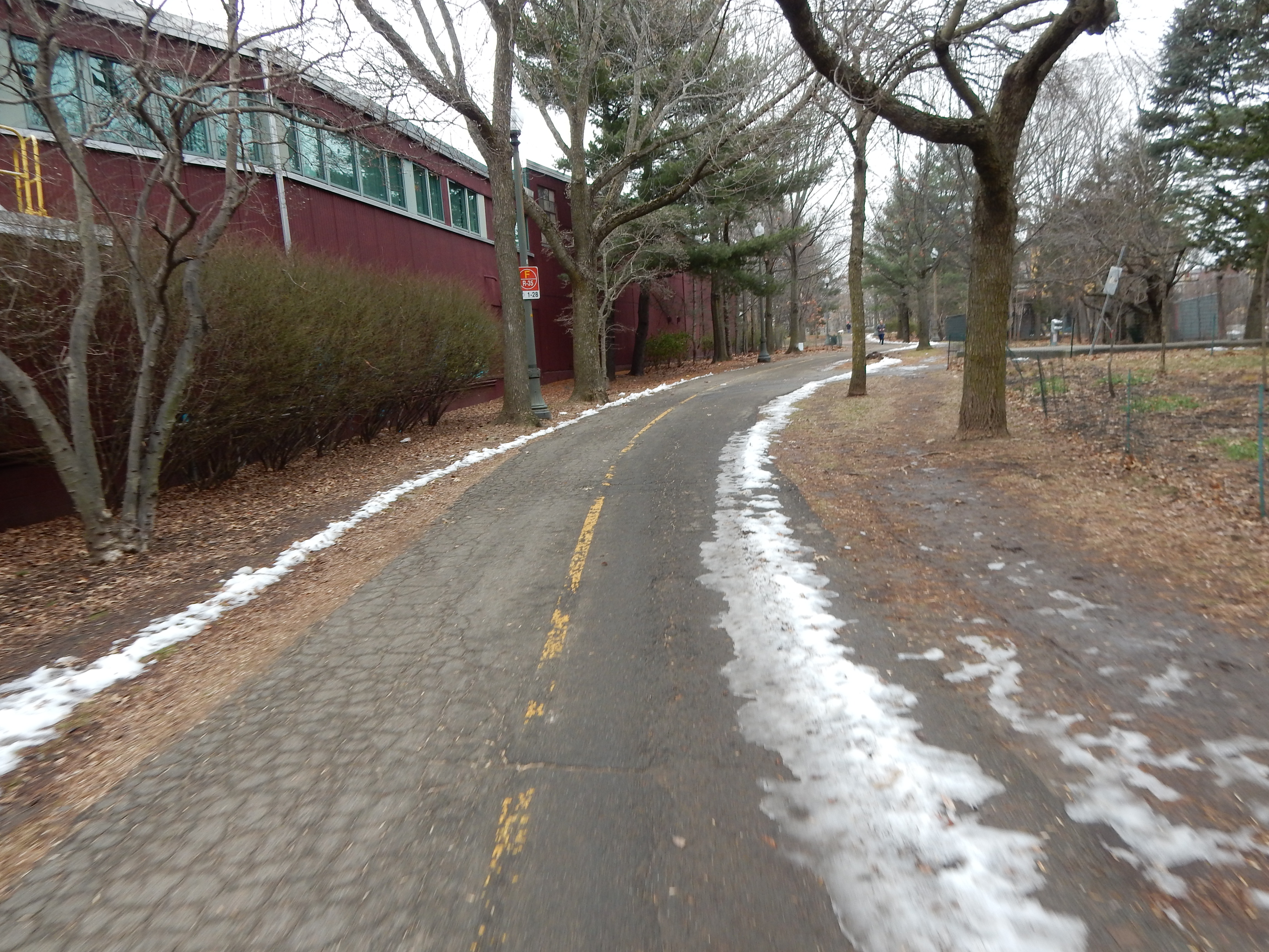 Two-lane path with a line of snow next to a brick building