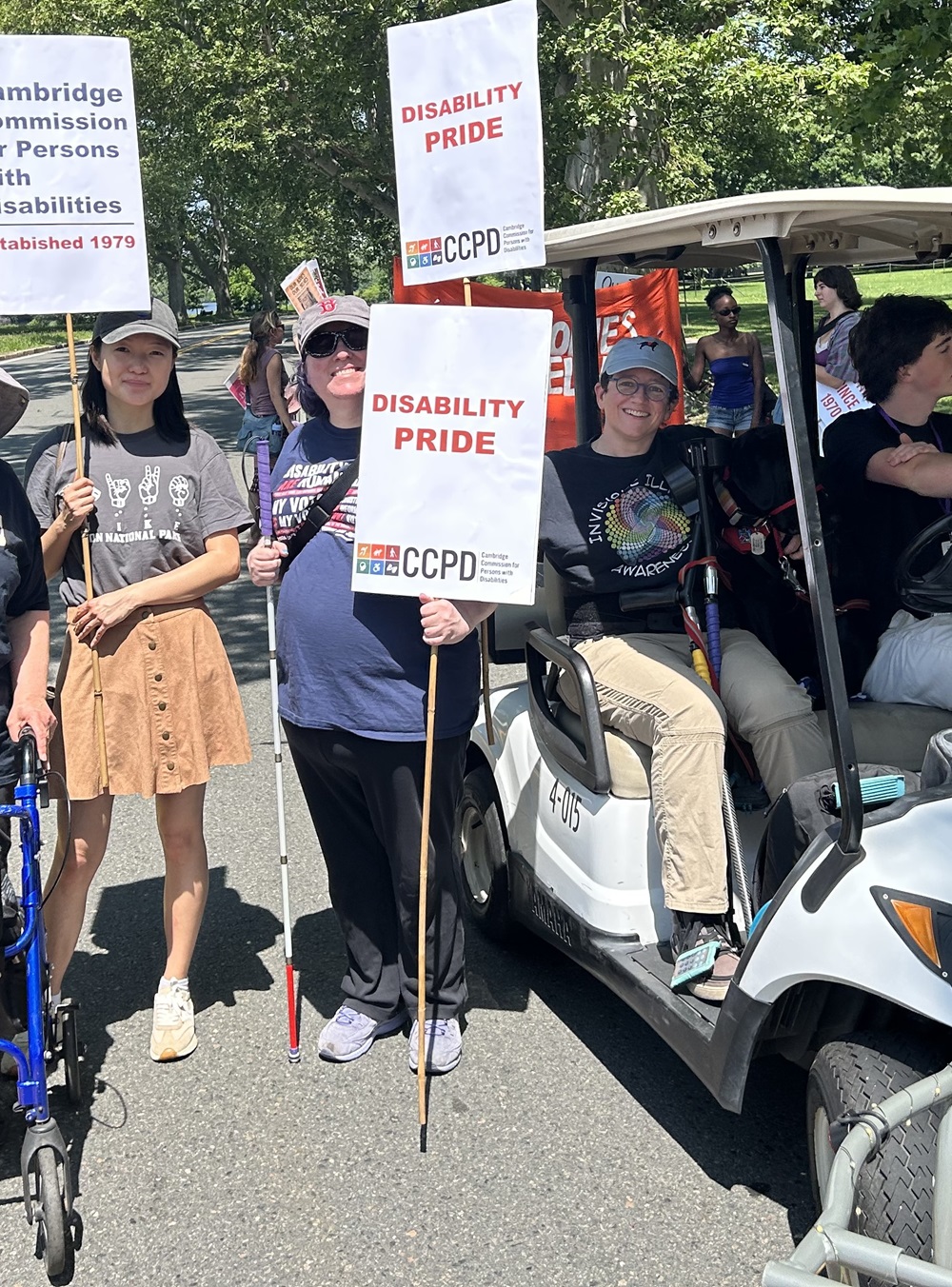 Rachel Tanenhaus (center), ADA Coordinator for the City of Cambridge, holds Disability Pride signs before marching with the Cambridge Commission for Disabilities staff and supporters during the Cambridge River Festival parade.
