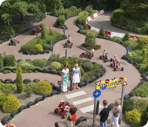 Children playing in a traffic garden while adults watch