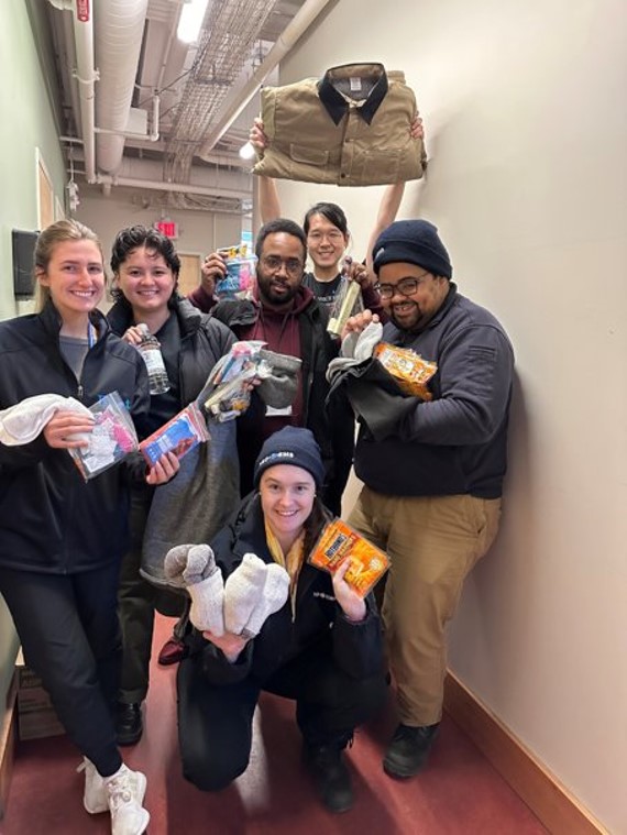 Cambridge outreach team members holding up supplies used in resource kits for unhoused residents. brining supplies