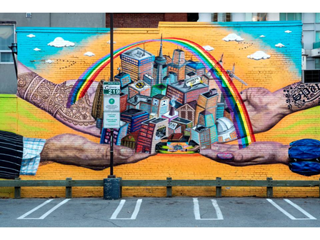 Mural of a rainbow over a city held up by four hands